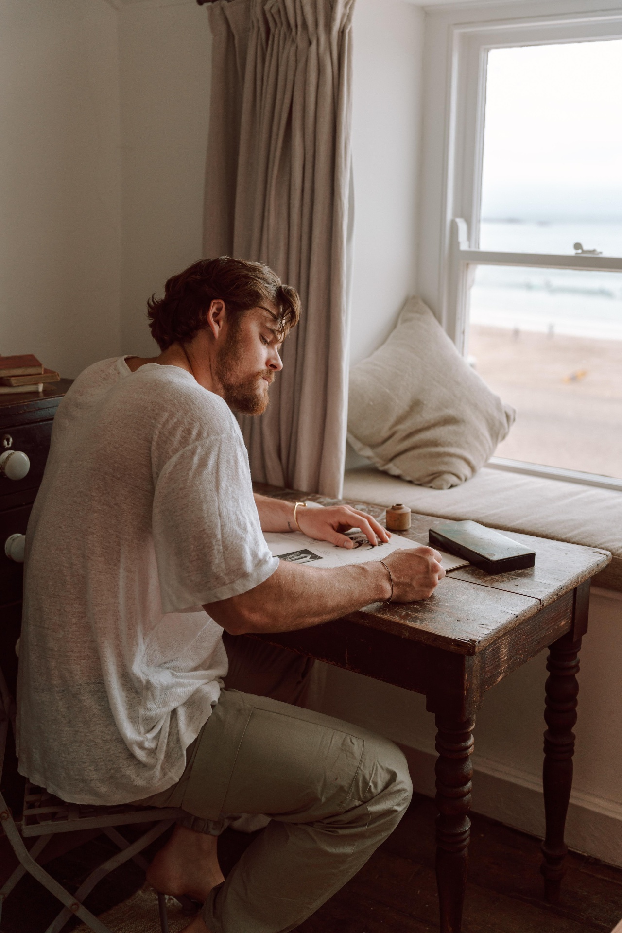 Ryan writing a letter at a desk beside the sea